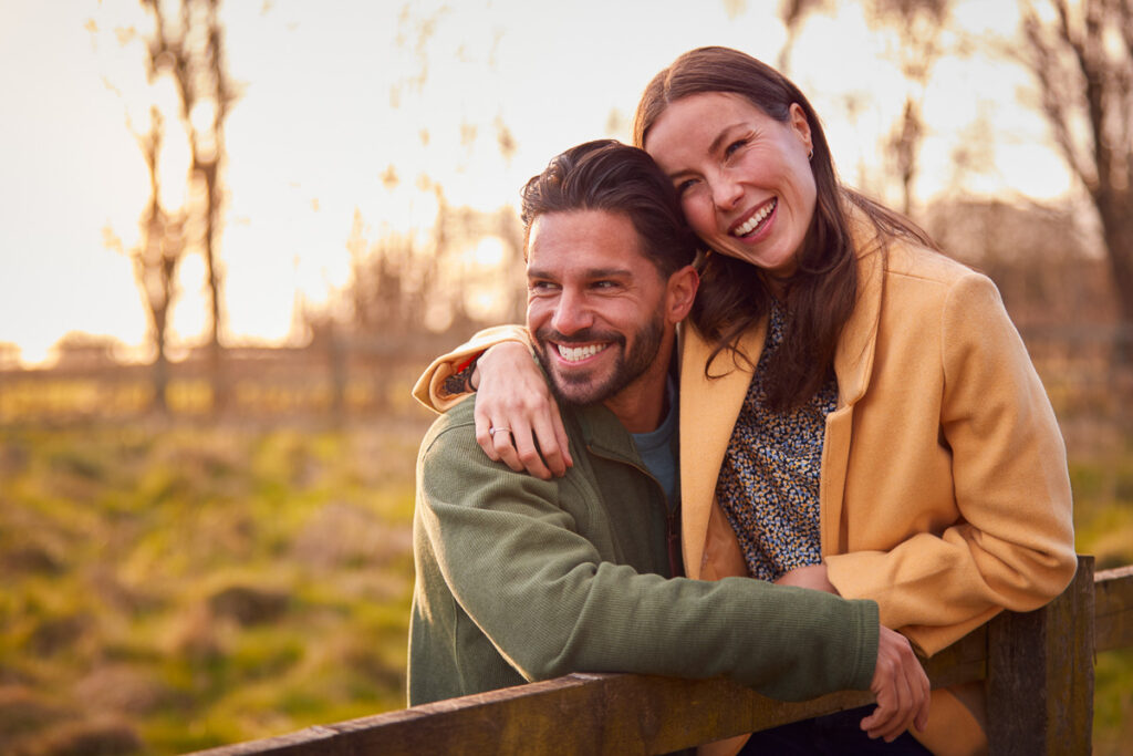 Loving,Couple,On,Walk,Through,Autumn,Countryside,Resting,On,Fence